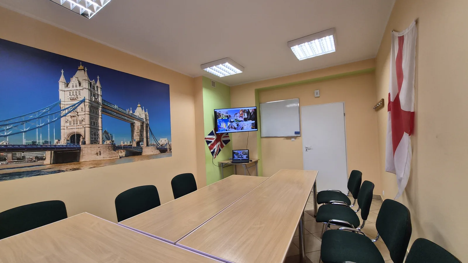 Sala szkoleniowa English Colours w Białymstoku - stoły, krzesła, telewizor, tablica suchościeralna i fototapeta z Tower Bridge